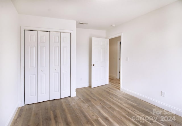 unfurnished bedroom featuring wood-type flooring and a closet