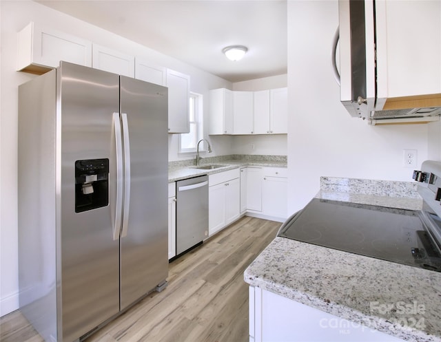 kitchen featuring white cabinetry, stainless steel appliances, light hardwood / wood-style flooring, light stone counters, and sink