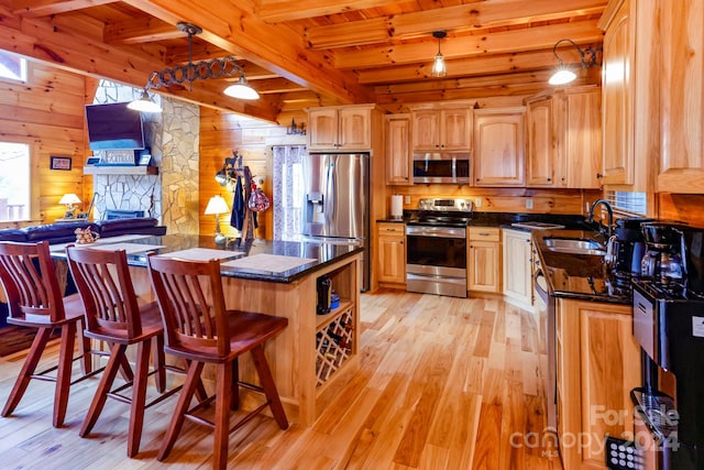 kitchen featuring appliances with stainless steel finishes, beam ceiling, light hardwood / wood-style floors, and sink