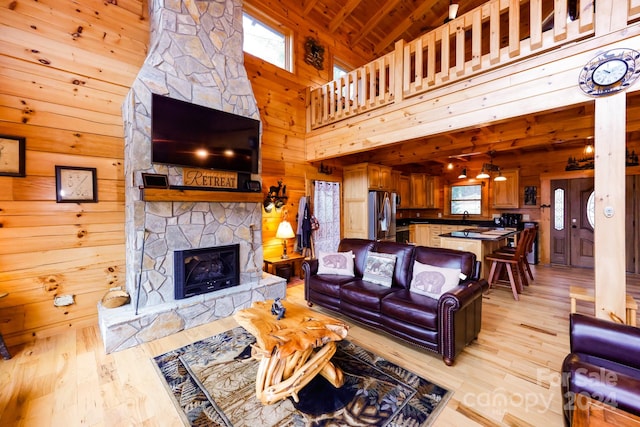 living room featuring high vaulted ceiling, a fireplace, wood ceiling, light hardwood / wood-style floors, and ceiling fan