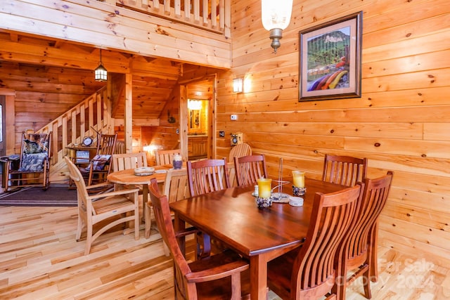 dining space with light hardwood / wood-style flooring and wood walls