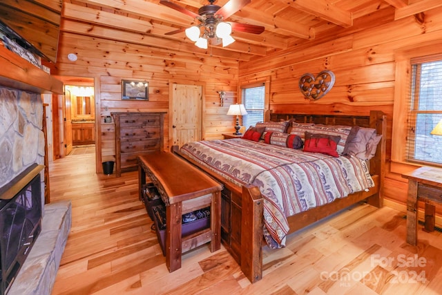 bedroom with beamed ceiling, ceiling fan, wooden walls, wooden ceiling, and light hardwood / wood-style flooring