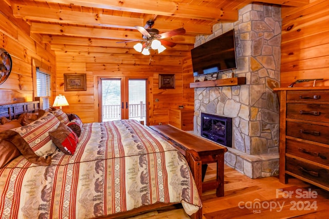 bedroom featuring beamed ceiling, a fireplace, light hardwood / wood-style floors, access to outside, and wooden ceiling