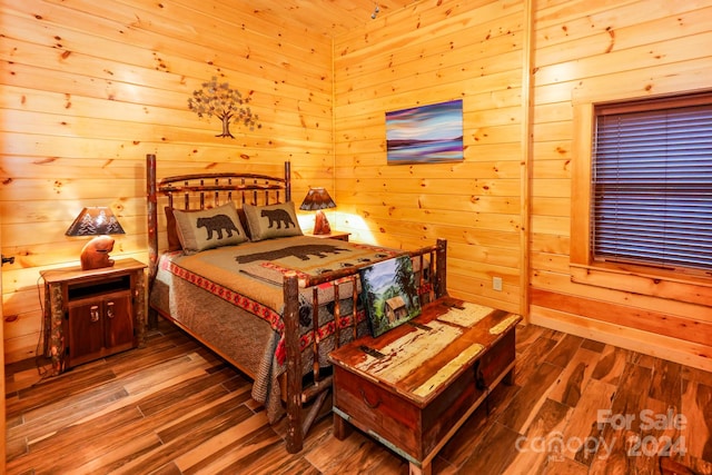 bedroom with wood walls and dark wood-type flooring