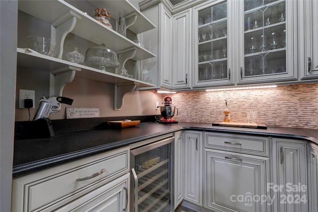 bar featuring white cabinetry, decorative backsplash, and beverage cooler