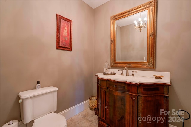 bathroom featuring tile patterned flooring, vanity, toilet, and a notable chandelier