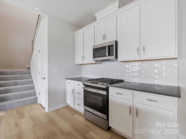 kitchen featuring backsplash, white cabinetry, light wood-type flooring, and appliances with stainless steel finishes