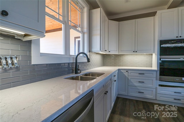 kitchen featuring sink, appliances with stainless steel finishes, light stone counters, tasteful backsplash, and white cabinets