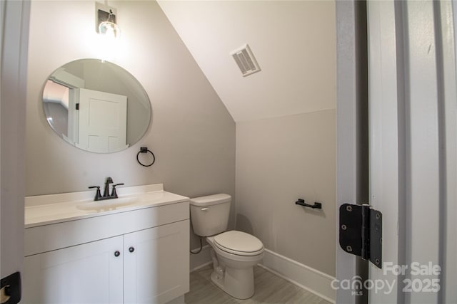 bathroom with vanity, vaulted ceiling, and toilet