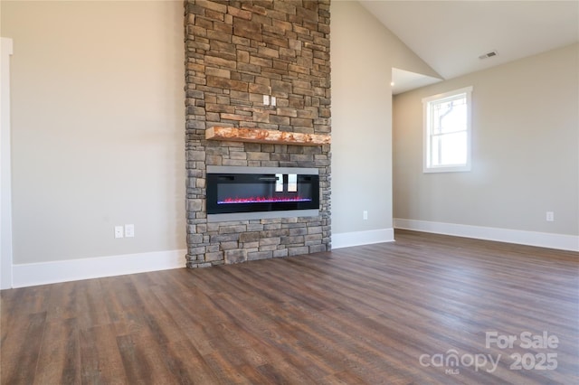 unfurnished living room featuring lofted ceiling, dark wood-type flooring, and a fireplace