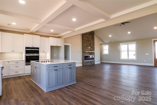 kitchen with white cabinetry, a kitchen island, dark wood-type flooring, and a fireplace