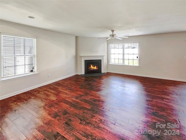 unfurnished living room featuring ceiling fan and dark wood-type flooring