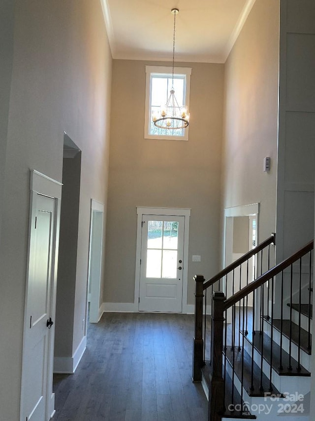 entrance foyer with ornamental molding, an inviting chandelier, plenty of natural light, and dark hardwood / wood-style flooring