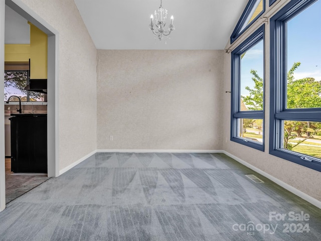 unfurnished room with light colored carpet, vaulted ceiling, and a chandelier