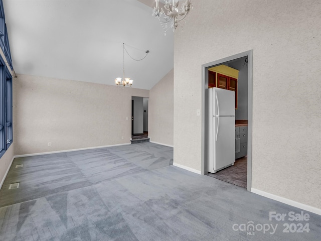 carpeted empty room with high vaulted ceiling and an inviting chandelier