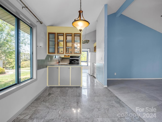 kitchen featuring lofted ceiling with beams, hanging light fixtures, light tile flooring, white fridge, and sink