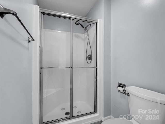 bathroom featuring a shower with shower door and toilet