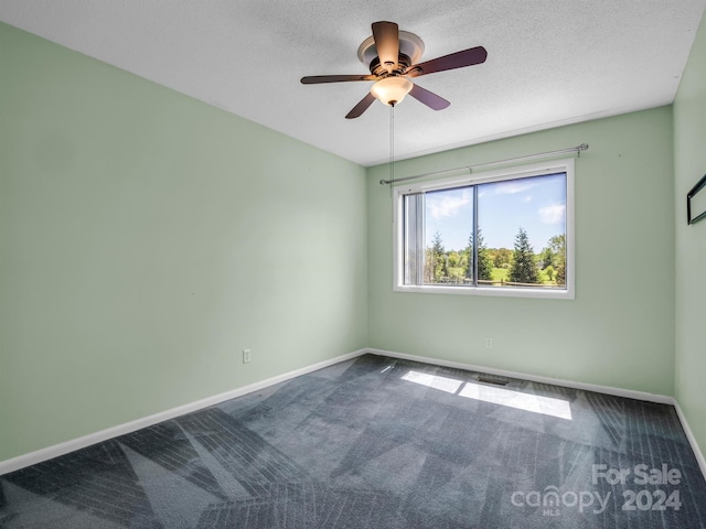 empty room featuring a textured ceiling, ceiling fan, and dark colored carpet