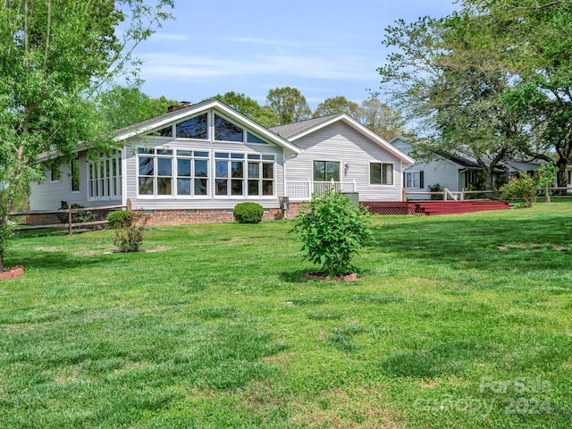 rear view of house with a deck and a lawn