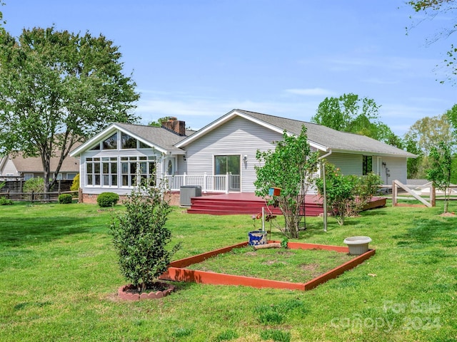 rear view of house featuring a deck, a yard, a sunroom, and central AC unit