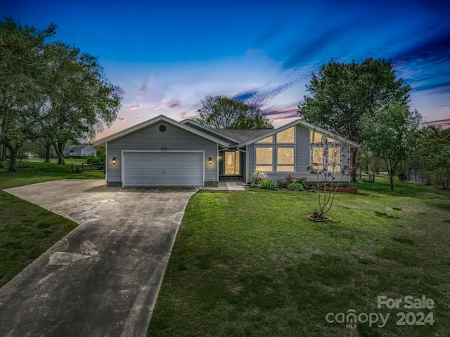 ranch-style house featuring a garage and a lawn