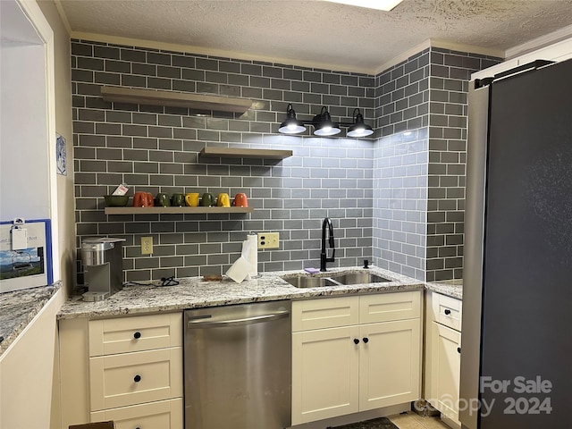 kitchen with sink, refrigerator, stainless steel dishwasher, and light stone counters