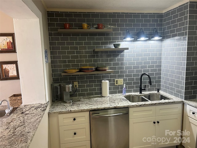 kitchen featuring white cabinets, sink, tasteful backsplash, stainless steel dishwasher, and light stone countertops