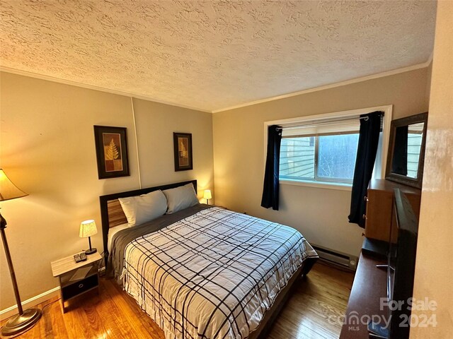 bedroom with a textured ceiling, dark wood-type flooring, and baseboard heating