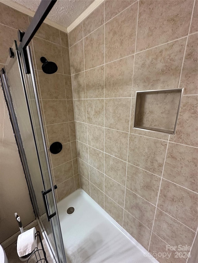 bathroom featuring walk in shower, crown molding, and a textured ceiling