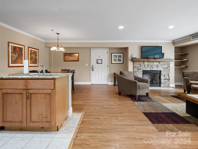 kitchen featuring light stone counters, hanging light fixtures, a fireplace, and light wood-type flooring