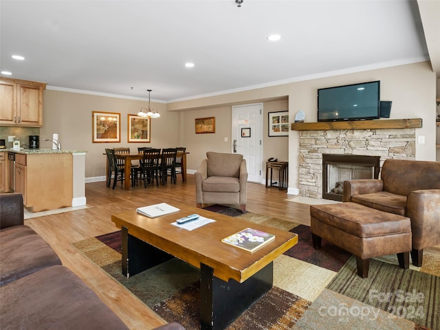 living room featuring ornamental molding, light hardwood / wood-style flooring, a fireplace, and an inviting chandelier