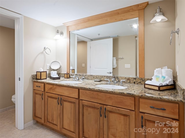 bathroom with dual sinks, toilet, tile flooring, and large vanity