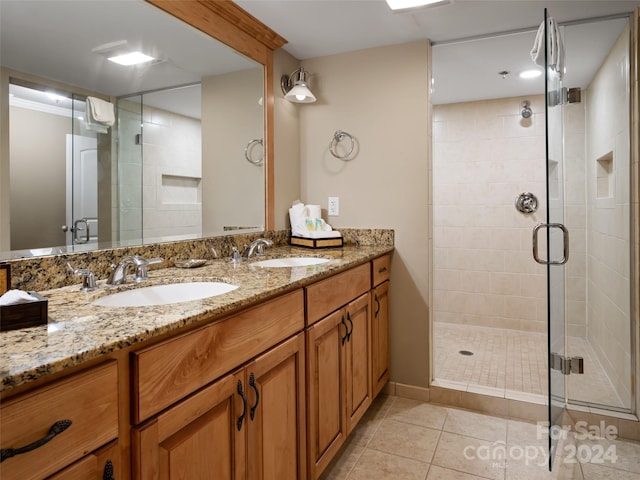 bathroom with oversized vanity, a shower with shower door, tile floors, and dual sinks