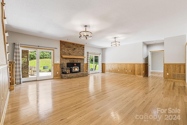 unfurnished living room featuring a brick fireplace, plenty of natural light, a textured ceiling, and an inviting chandelier