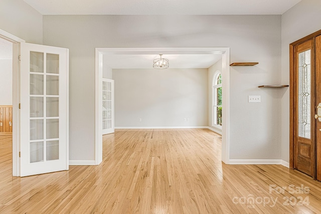 foyer with a chandelier, french doors, and light wood-type flooring