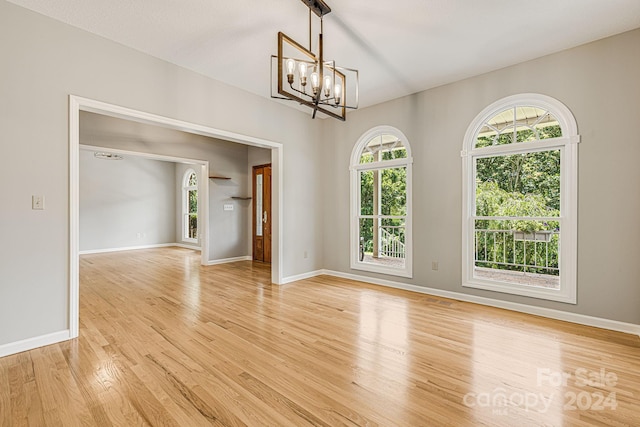 spare room with light hardwood / wood-style floors and an inviting chandelier