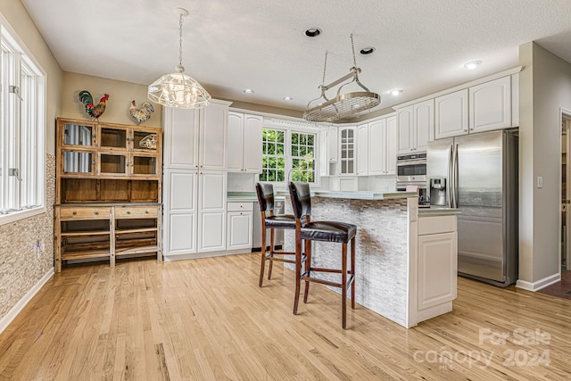 kitchen with white cabinets, a center island, stainless steel appliances, and hanging light fixtures