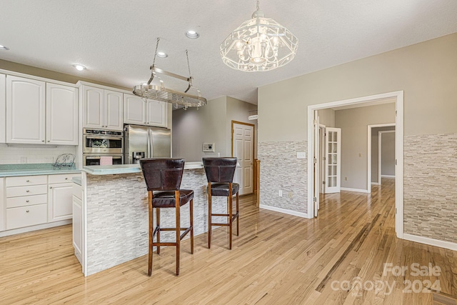 kitchen featuring white cabinetry, stainless steel appliances, a textured ceiling, decorative light fixtures, and decorative backsplash