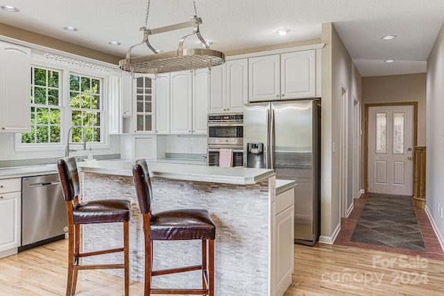 kitchen featuring tasteful backsplash, a center island, white cabinets, and appliances with stainless steel finishes