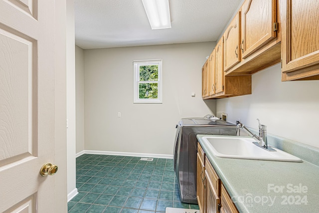 clothes washing area with separate washer and dryer, sink, and cabinets