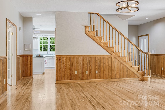 stairway with hardwood / wood-style flooring, sink, and an inviting chandelier