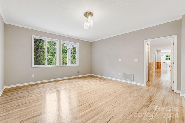 unfurnished room featuring light hardwood / wood-style floors, crown molding, and a wealth of natural light