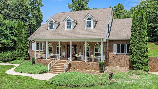 new england style home with covered porch and a front lawn