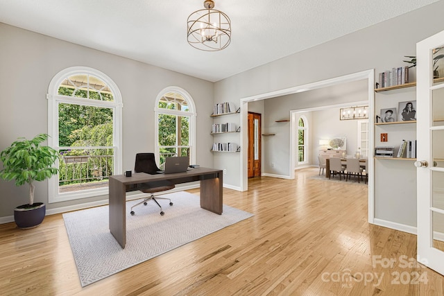 office area featuring light wood-type flooring, a textured ceiling, and a chandelier