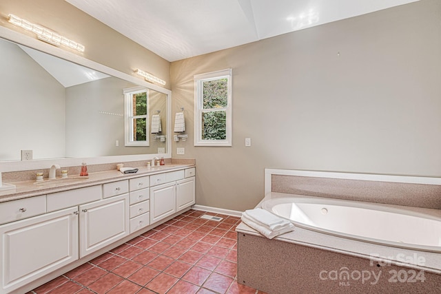 bathroom featuring tile patterned flooring, vanity, tiled tub, and vaulted ceiling