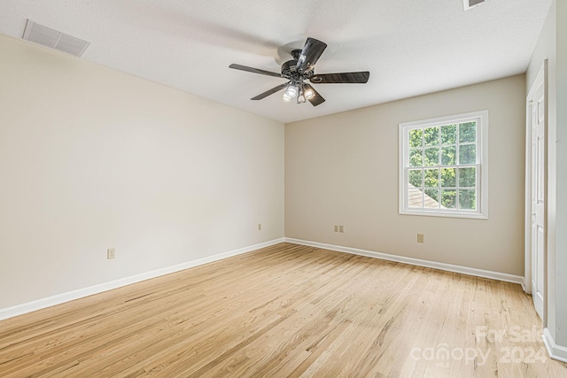 unfurnished room featuring ceiling fan, light wood-type flooring, and a textured ceiling