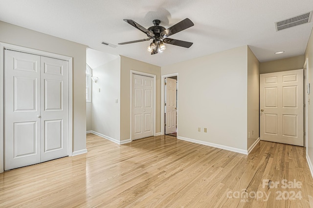 unfurnished bedroom featuring light wood-type flooring, two closets, and ceiling fan