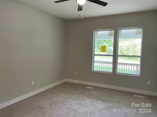 carpeted spare room featuring a wealth of natural light and ceiling fan