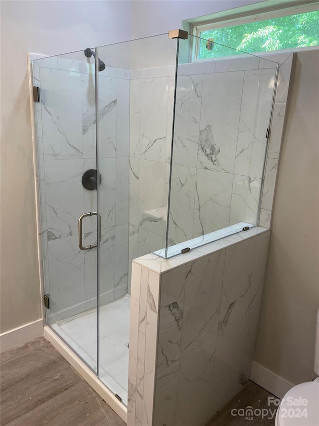 bathroom with hardwood / wood-style floors, an enclosed shower, and toilet