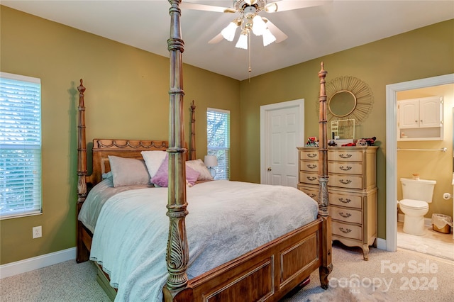 bedroom with multiple windows, ensuite bathroom, ceiling fan, and light carpet